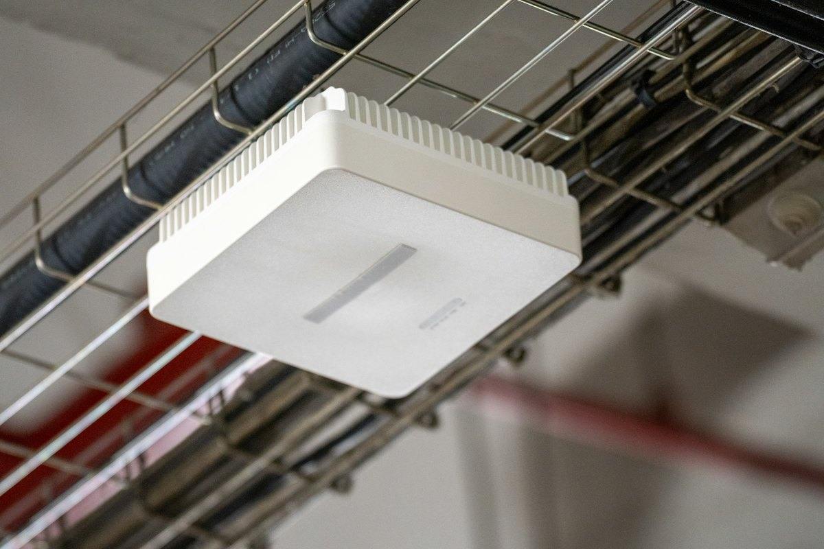 White Wi-Fi access point on a ceiling cable tray